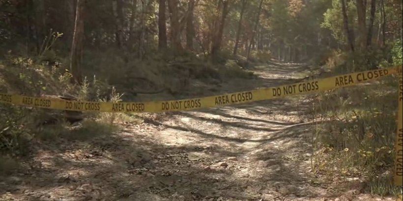 Forest path with police tape across it.