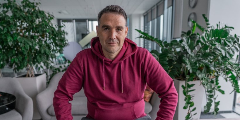 David Pokleka wearing a wearing hoodie and sitting  between two plants